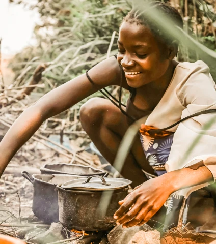 African woman cooking in pots over a fire